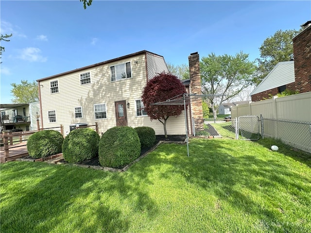 back of property featuring fence, a yard, and a chimney