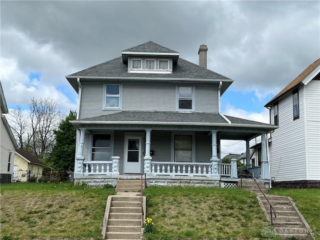 view of front of property featuring a front yard, roof with shingles, a chimney, a porch, and stairway