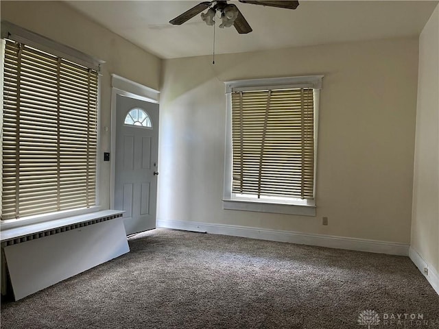 carpeted foyer with a ceiling fan and baseboards