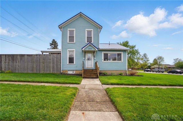 view of front of house featuring fence, metal roof, and a front yard