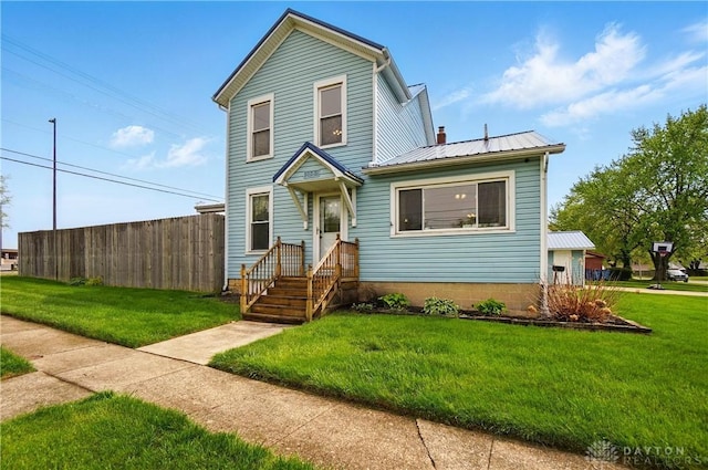 traditional-style home featuring a chimney, fence, metal roof, and a front lawn