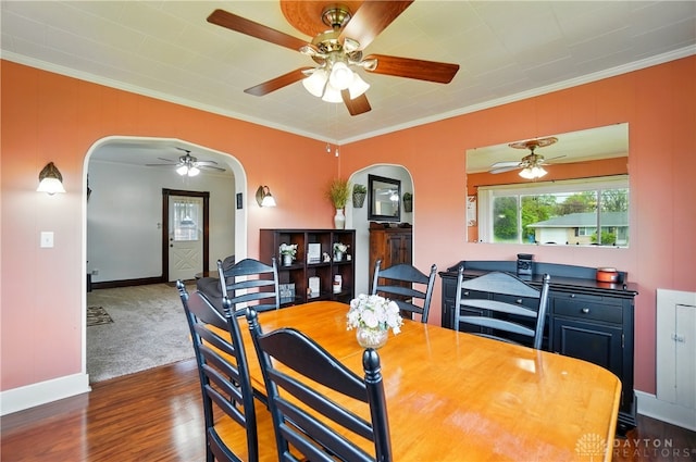 dining space with a ceiling fan, crown molding, arched walkways, wood finished floors, and baseboards