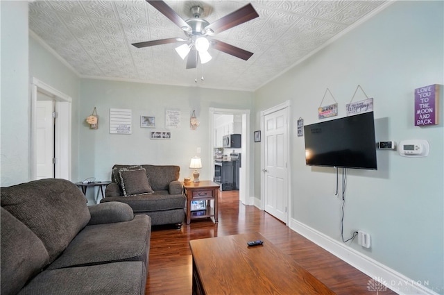 living area with crown molding, a ceiling fan, dark wood-style flooring, and an ornate ceiling