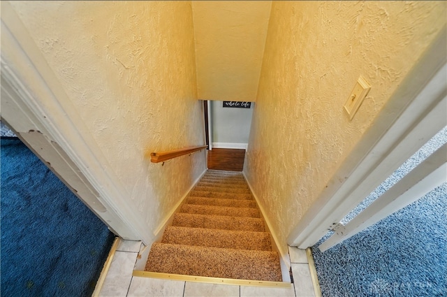 stairs with baseboards and a textured wall