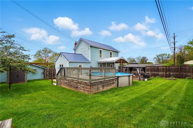 rear view of property with a fenced backyard, a shed, a fenced in pool, a gazebo, and a yard