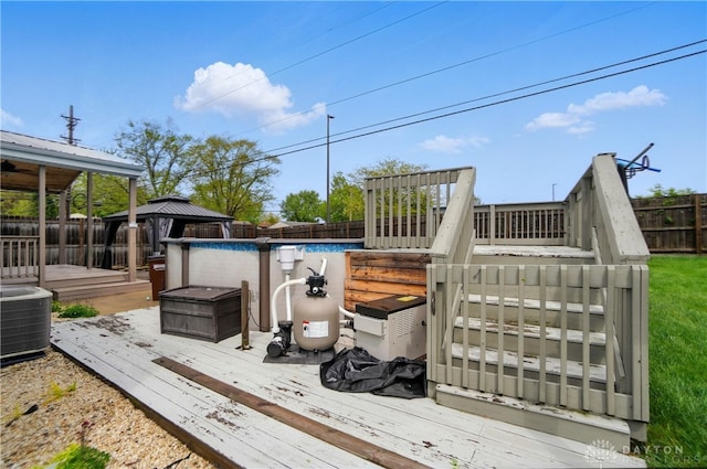 deck with a gazebo, a fenced in pool, central AC unit, and a fenced backyard
