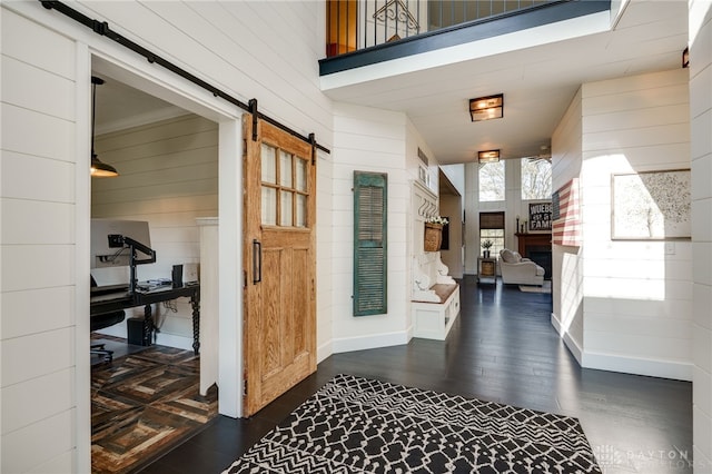 interior space with wooden walls, dark wood-style floors, and a barn door