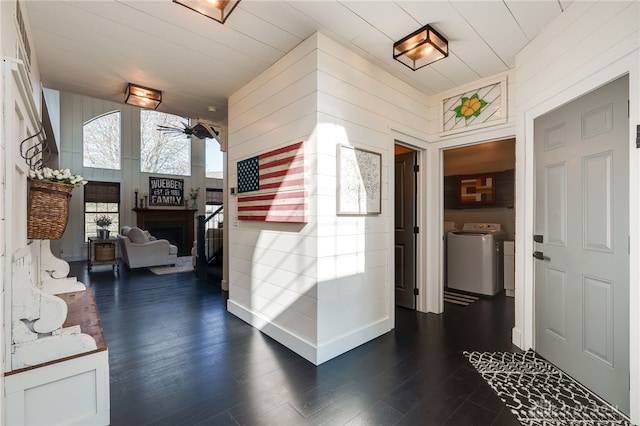 interior space featuring washer and clothes dryer, wooden walls, dark wood-style floors, and a fireplace