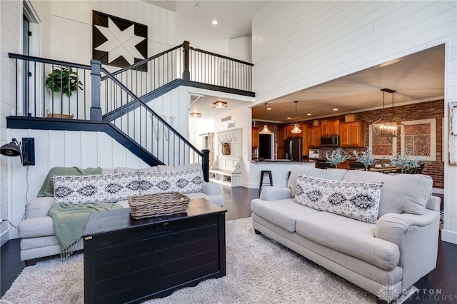 living room with a chandelier, stairs, recessed lighting, wood finished floors, and a towering ceiling