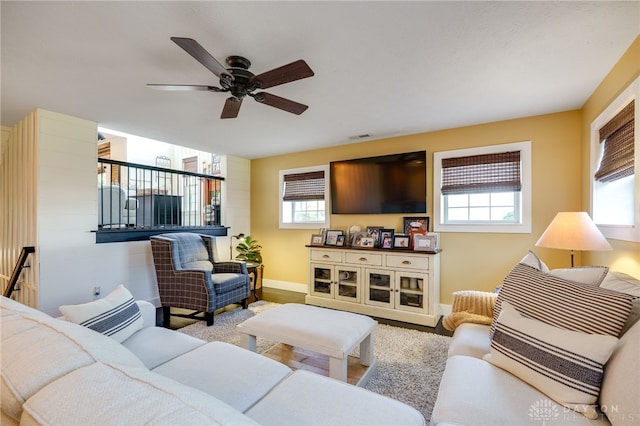 living area featuring ceiling fan, visible vents, baseboards, and wood finished floors