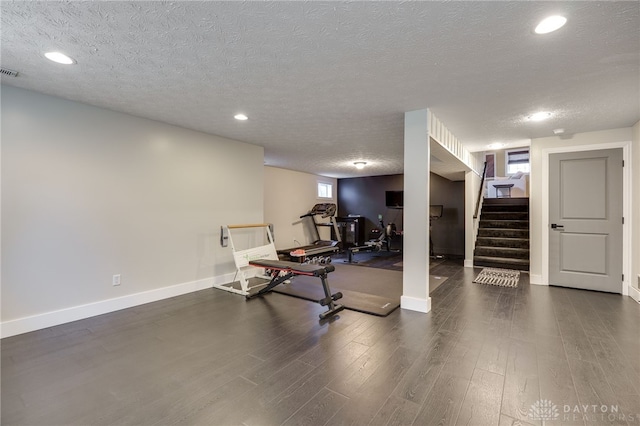 workout area featuring baseboards, a textured ceiling, and wood finished floors