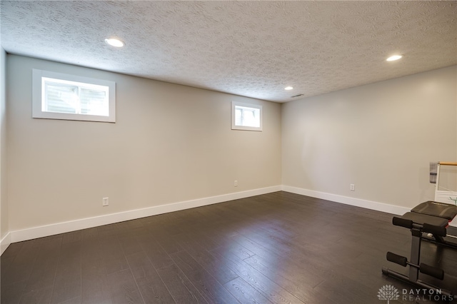 basement featuring baseboards, recessed lighting, a textured ceiling, and dark wood-style floors