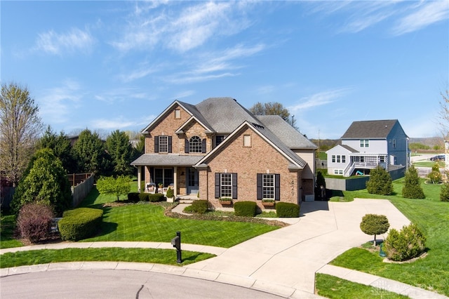traditional-style house with fence, brick siding, a porch, a front yard, and driveway