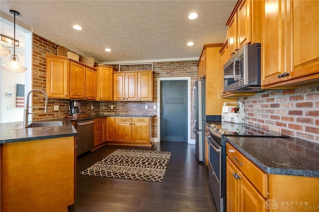 kitchen featuring a textured ceiling, brown cabinets, a sink, dark wood finished floors, and stainless steel appliances