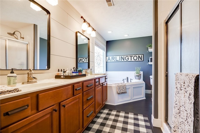 full bathroom with a sink, double vanity, a shower stall, visible vents, and a garden tub