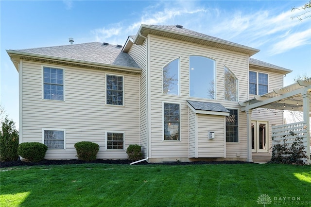 back of property with a lawn and roof with shingles