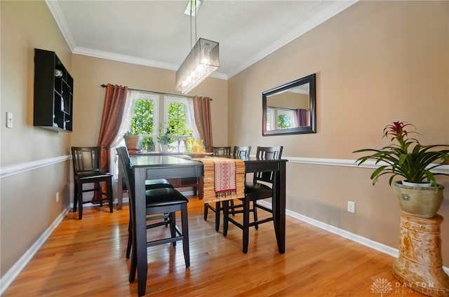 dining room featuring crown molding, light wood-style flooring, and baseboards