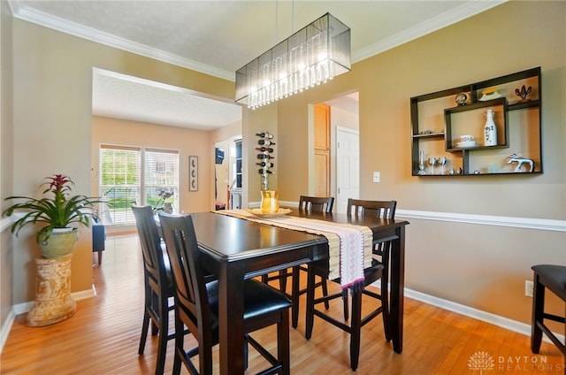 dining area featuring baseboards, crown molding, and wood finished floors
