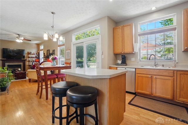 kitchen with stainless steel dishwasher, a sink, a wealth of natural light, and a center island
