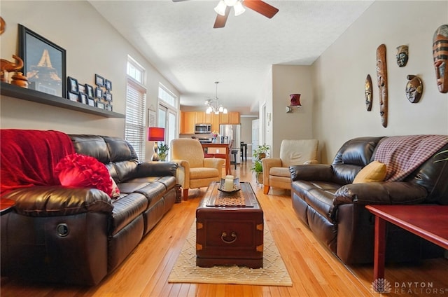 living room featuring ceiling fan with notable chandelier and light wood-style floors