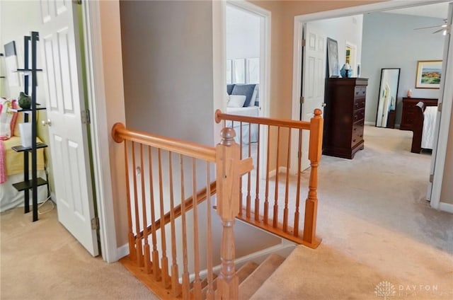 corridor with baseboards, carpet, and an upstairs landing
