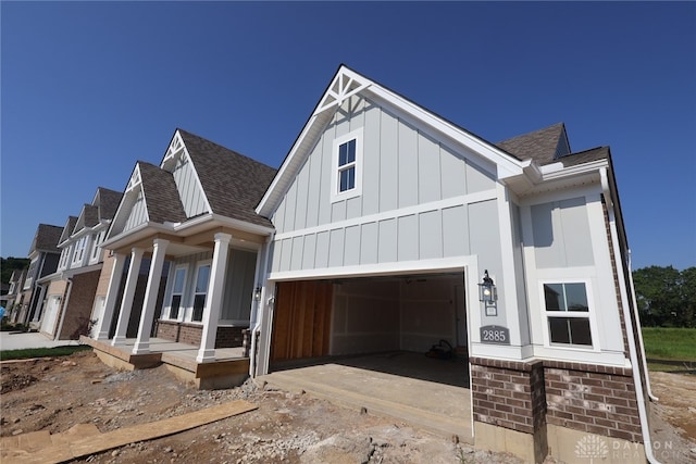 2885 Sky Crossing Dr Unit 56, Beavercreek, OH 45434 - view of front facade featuring a shingled roof, board and batten siding, a porch, and brick siding