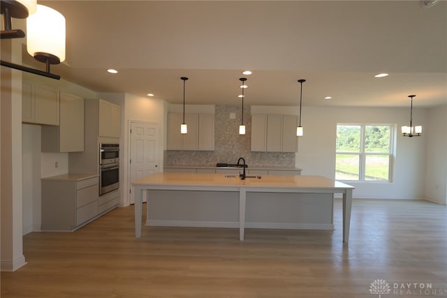2885 Sky Crossing Dr Unit 56, Beavercreek, OH 45434 - kitchen with tasteful backsplash, stainless steel double oven, light wood-type flooring, a spacious island, and recessed lighting