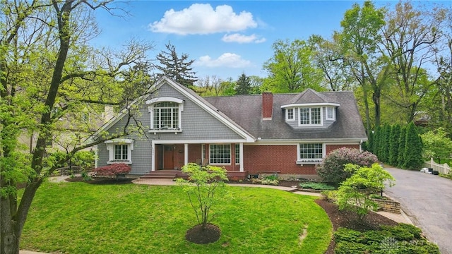 view of front of property with brick siding, driveway, and a front lawn
