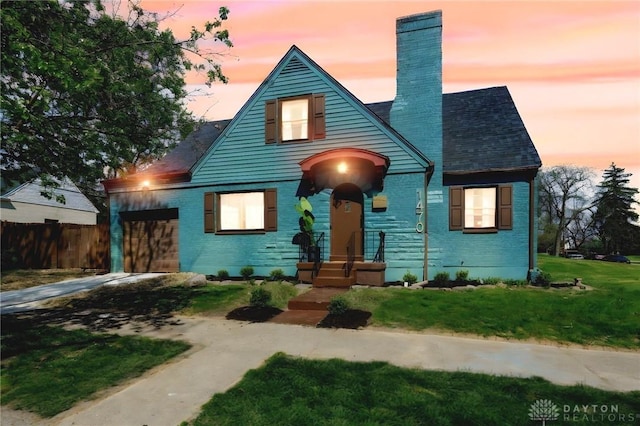 bungalow-style home featuring a chimney, brick siding, fence, a front lawn, and concrete driveway