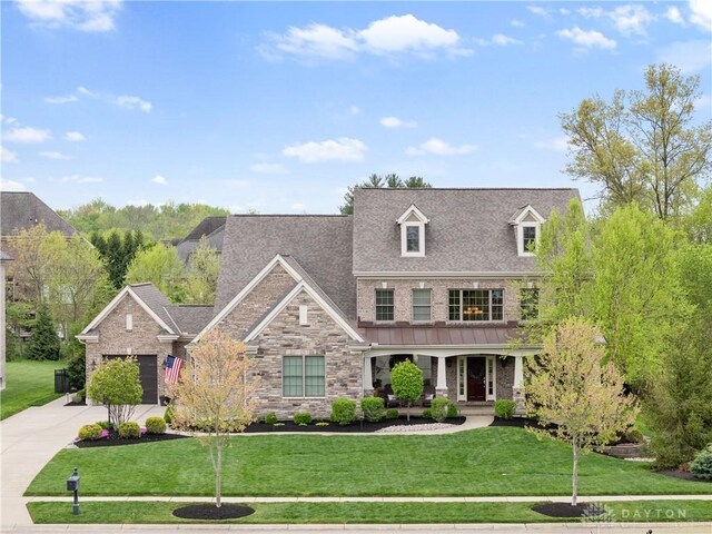 view of front of house with a front lawn, stone siding, a garage, a porch, and concrete driveway