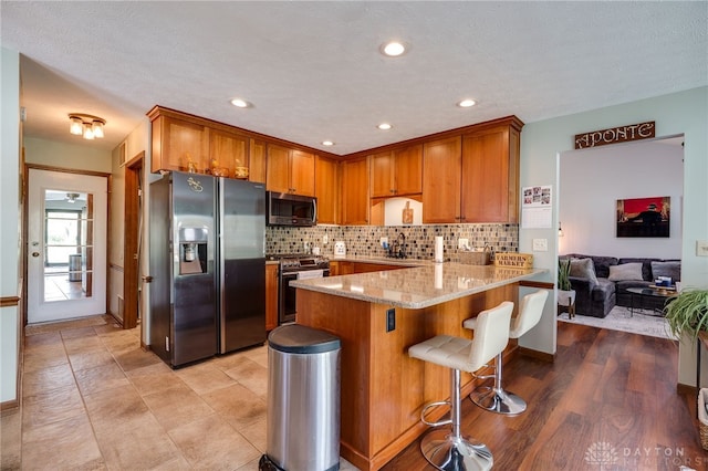 717 Walden Way, Dayton, OH 45440 - kitchen featuring a peninsula, stainless steel appliances, brown cabinets, and backsplash