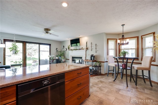 717 Walden Way, Dayton, OH 45440 - kitchen featuring ceiling fan with notable chandelier, brown cabinetry, baseboards, a glass covered fireplace, and dishwasher
