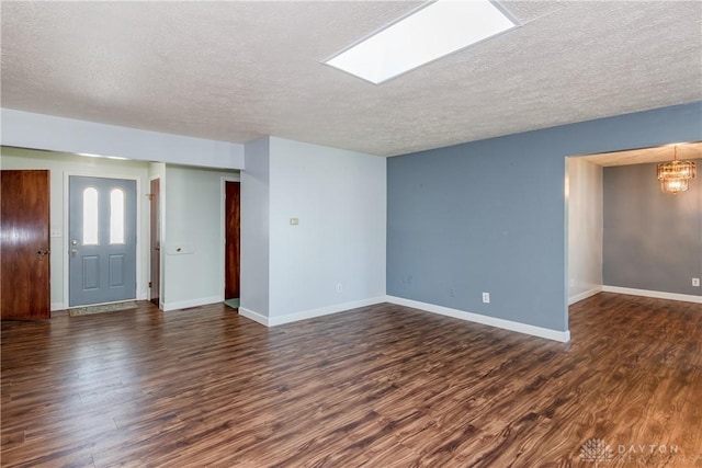 unfurnished living room featuring a notable chandelier, a textured ceiling, and dark wood finished floors