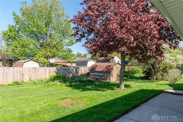 view of yard featuring a storage unit, an outbuilding, and fence private yard