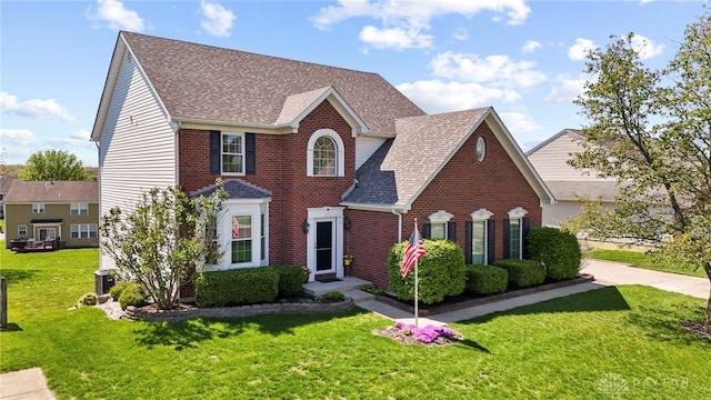 view of front of home featuring brick siding, a shingled roof, and a front yard