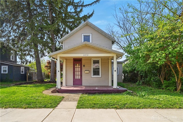 shotgun-style home featuring a porch and a front yard