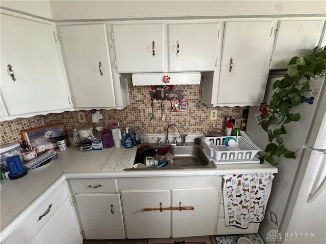 kitchen featuring light countertops, tasteful backsplash, white cabinetry, and a sink