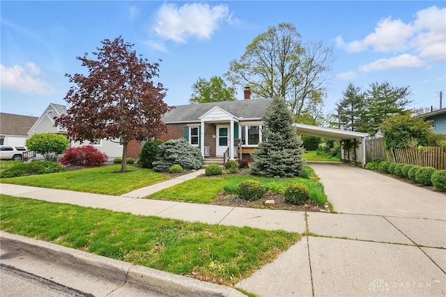 view of front facade featuring a front lawn, fence, a chimney, concrete driveway, and a carport