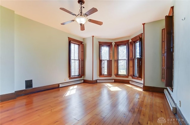 empty room featuring a baseboard heating unit, baseboard heating, and light wood finished floors