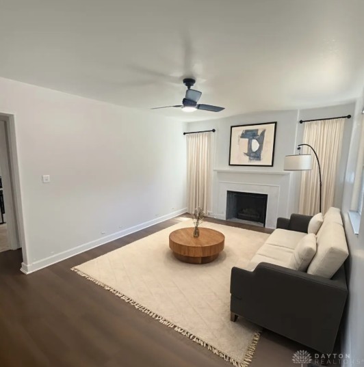 944 Wilmington Ave, Dayton, OH 45420 - living area with dark wood-style floors, ceiling fan, a fireplace with flush hearth, and baseboards