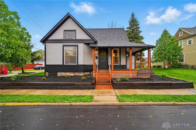 bungalow-style home with a porch, central AC unit, and a shingled roof