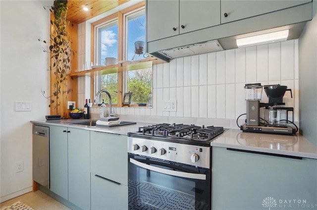 kitchen featuring light countertops, under cabinet range hood, a sink, appliances with stainless steel finishes, and backsplash