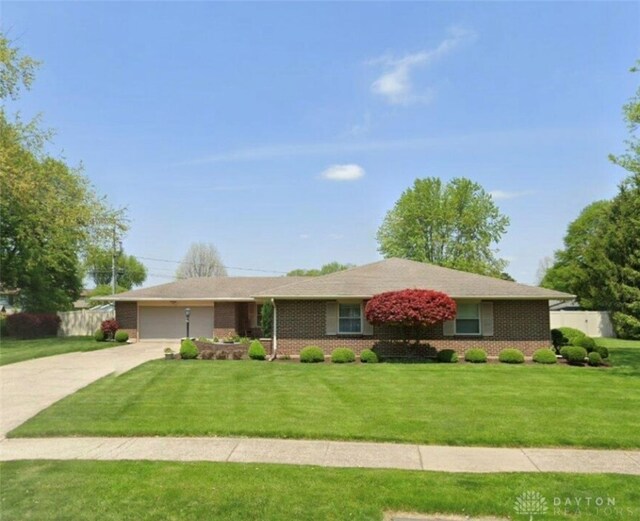 ranch-style house with an attached garage, concrete driveway, a front yard, and brick siding