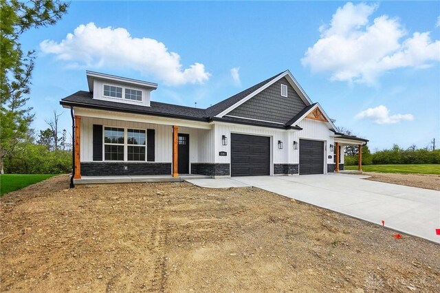 2061 Pine Forest Dr, Miamisburg, OH 45342 - view of front of property with a garage, covered porch, stone siding, board and batten siding, and driveway