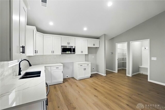 2061 Pine Forest Dr, Miamisburg, OH 45342 - kitchen featuring a sink, stainless steel microwave, lofted ceiling, backsplash, and visible vents