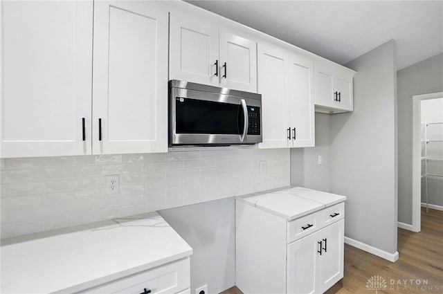 2061 Pine Forest Dr, Miamisburg, OH 45342 - kitchen featuring light wood-style floors, decorative backsplash, stainless steel microwave, and light stone countertops
