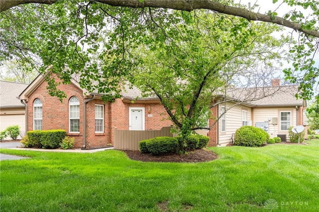 exterior space with brick siding, a chimney, and a front yard