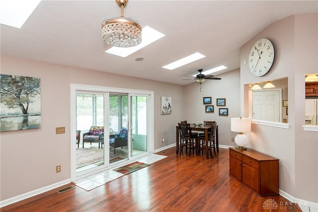 dining area with baseboards, visible vents, wood finished floors, and vaulted ceiling with skylight