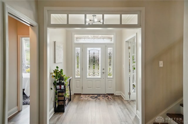 foyer entrance featuring baseboards, plenty of natural light, and light wood-type flooring