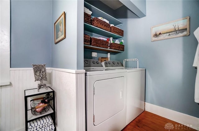 laundry area with washing machine and clothes dryer, laundry area, wainscoting, and wood finished floors